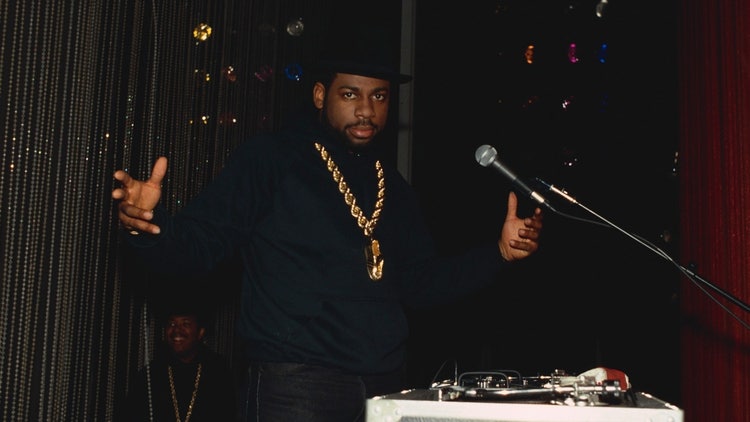 A person wearing a gold necklace and a hat Description automatically generated