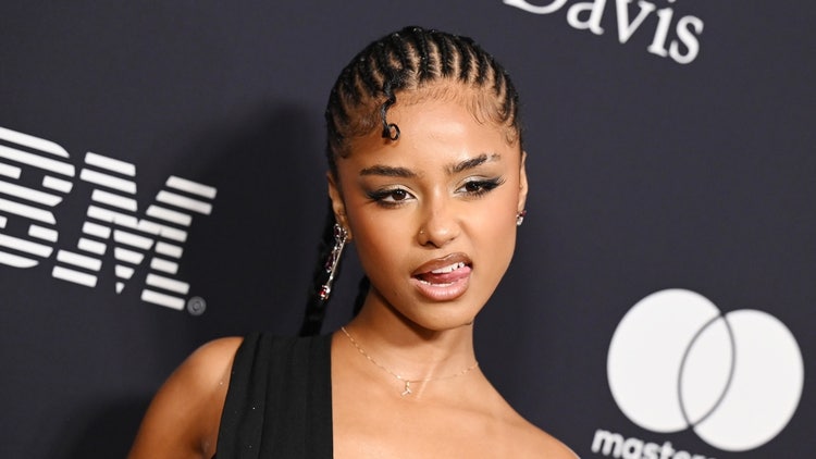 A person with braids in a black dress Description automatically generated